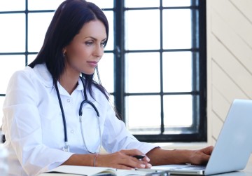 A-healthcare-professional-is-seen-using-a-mobile-to-attend-paid-medical-survey-infront-of-her-laptop